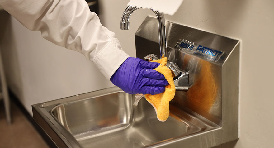 Wiping Industrial Sink with Sanitizing Wipe
