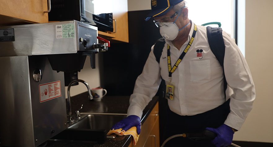 Wiping Industrial Coffee Maker with Sanitizing Wipe