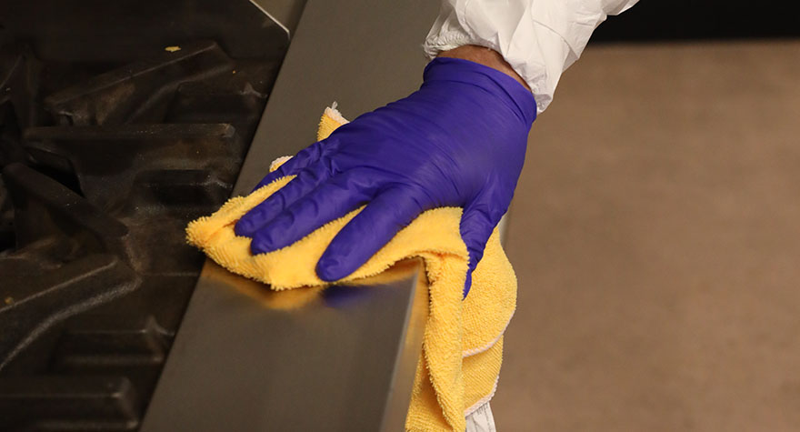 Wiping Industrial Stove with Sanitizing Wipe