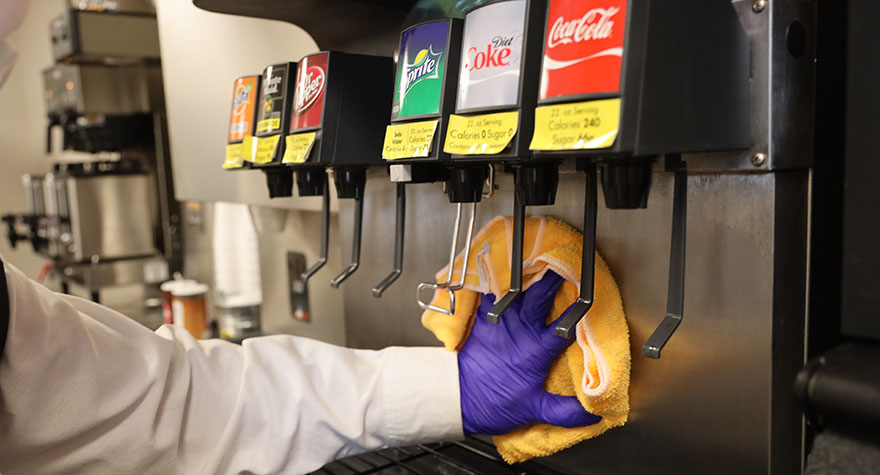 Wiping Soda Machine with Sanitizing Wipe