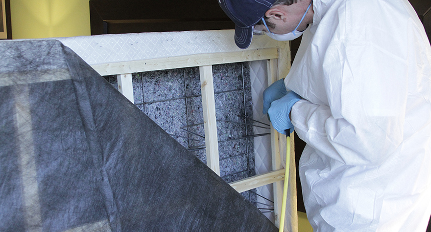 Pest professional applying boxspring treatment 