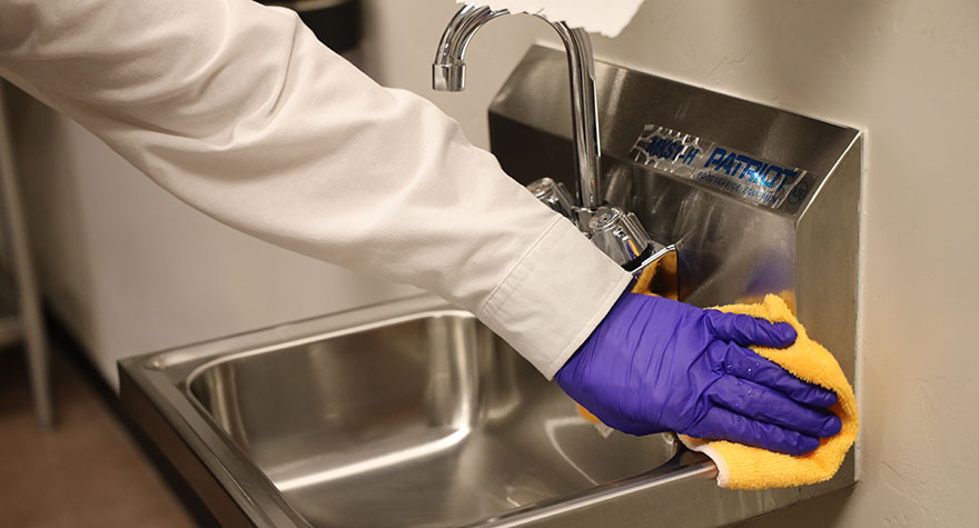 Wiping Industrial Sink with Sanitizing Wipe